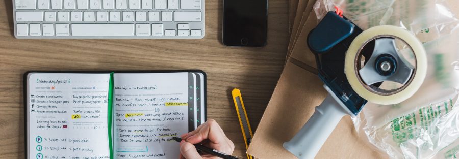 persoon aan het werk met toetsenbord, telefoon en aantekeningen